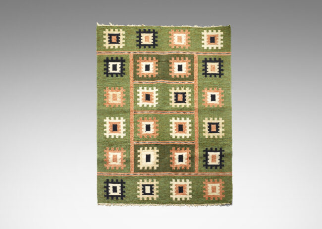 Gallery BAC Flat-weave carpet with folk-inspired pattern of notched squares in peach, ivory and black on a grass-green field, subdivided by linear elements