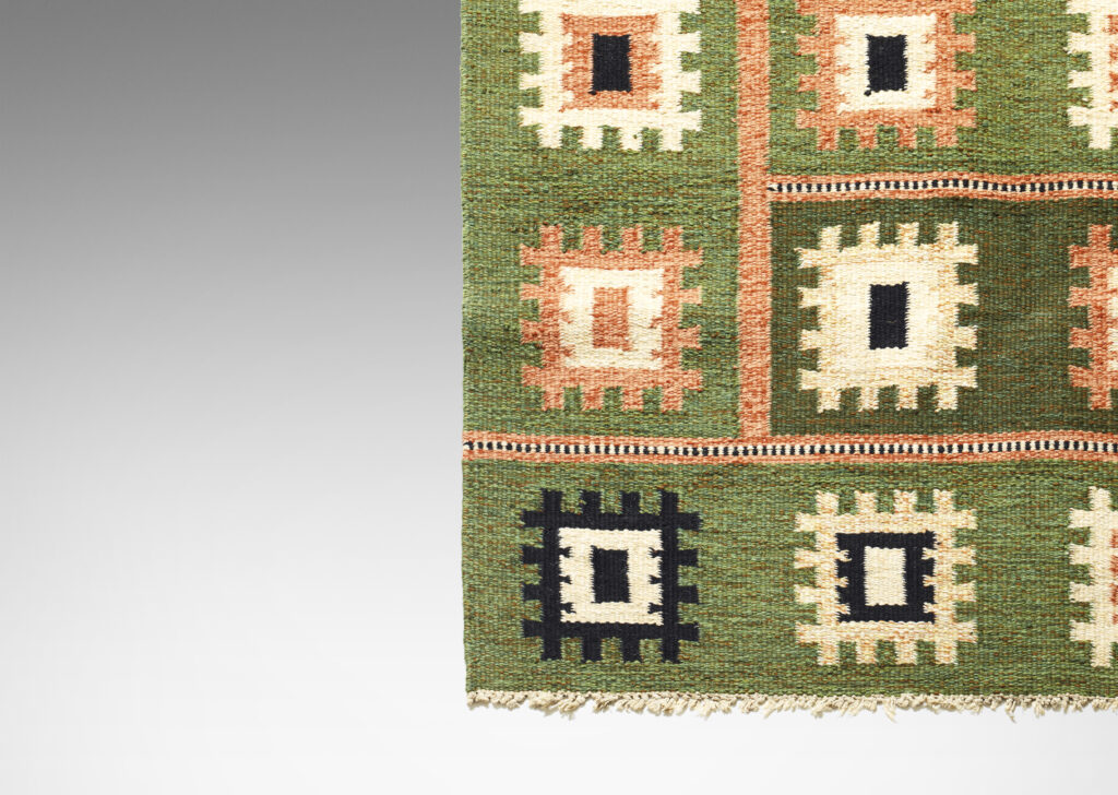 Gallery BAC Flat-weave carpet with folk-inspired pattern of notched squares in peach, ivory and black on a grass-green field, subdivided by linear elements