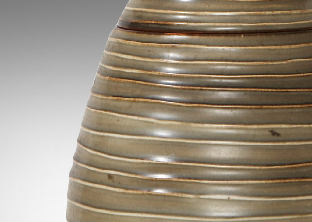 Gallery BAC Hand-thrown lidded jar with horizontal channels and shell ornament in stoneware with moody green glaze by Ebbe Sadolin