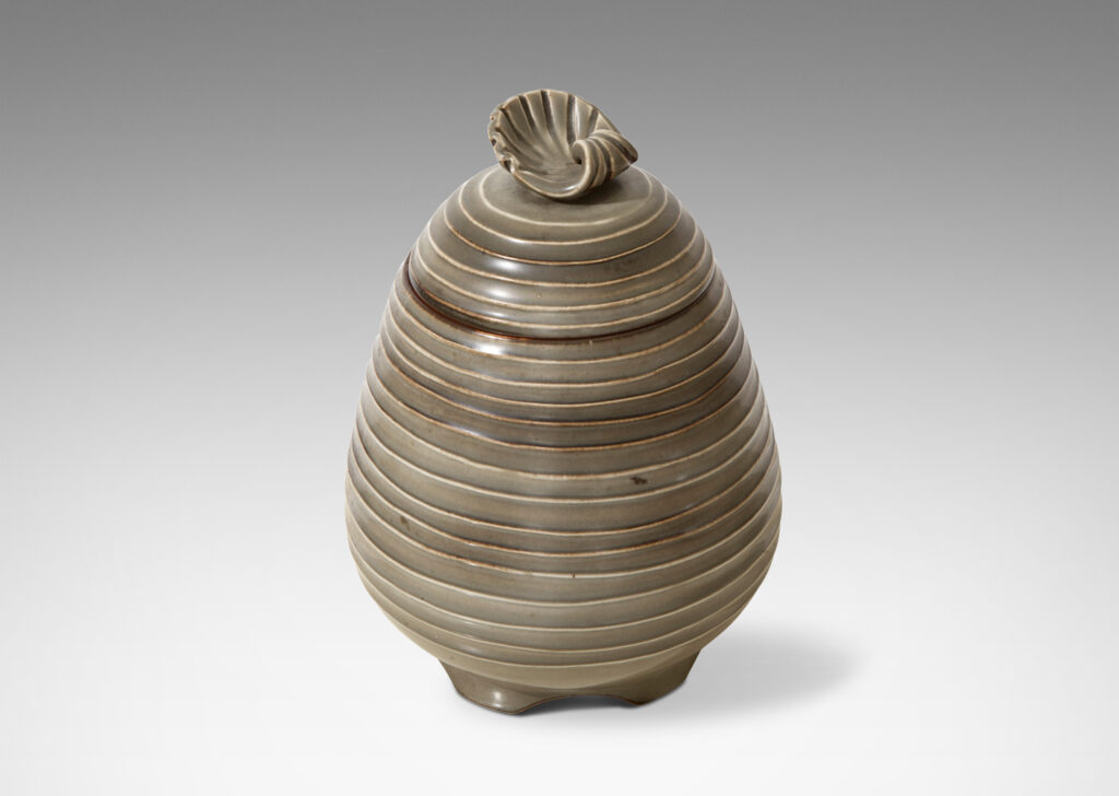 Gallery BAC Hand-thrown lidded jar with horizontal channels and shell ornament in stoneware with moody green glaze by Ebbe Sadolin