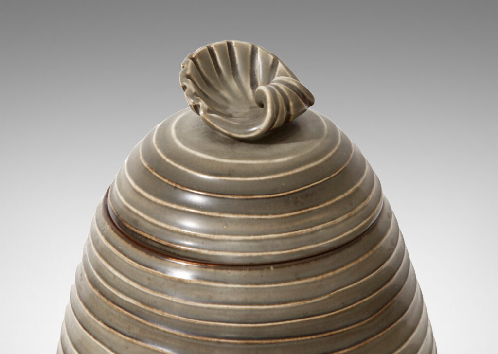 Gallery BAC Hand-thrown lidded jar with horizontal channels and shell ornament in stoneware with moody green glaze by Ebbe Sadolin