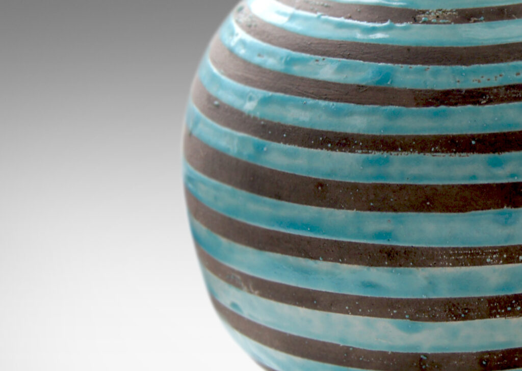 Gallery BAC spherical body with outstretched neck/mouth, perched on a low reveal foot, crafted in gray earthenware partially glazed in dimensionally thick pale aqua stripes