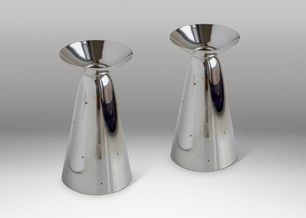 Gallery BAC combination vases / candlesticks each consisting of a conical form mounted to a modeled disk, which when set on the cone end is a candlestick with the disk functioning as a bobeche around a socket, and when set on the disk end is a vase