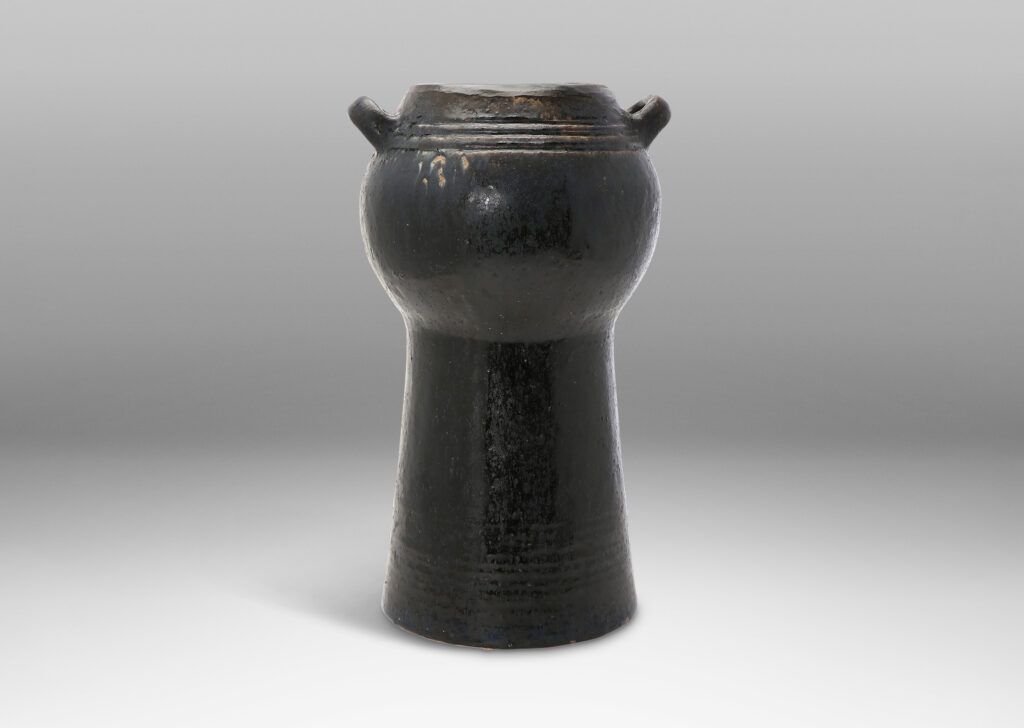 Gallery BAC spherical form with two handles on an engaged conical stand; hand-thrown stoneware with a moody black/blue/brown glaze