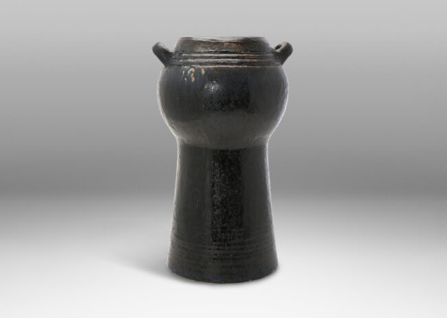 Gallery BAC spherical form with two handles on an engaged conical stand; hand-thrown stoneware with a moody black/blue/brown glaze