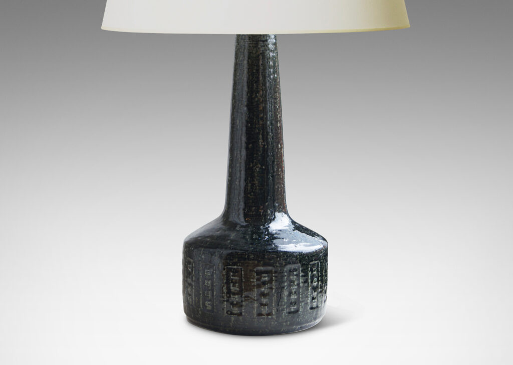 Gallery BAC low drum form with carved geometric design and tall neck; crafted in textured grog stoneware and glazed in a dark gray-green