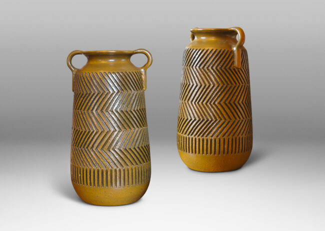 Gallery BAC raked cylindrical forms with cove necks and handles, and featuring the designer’s trademark carved graphic patterning