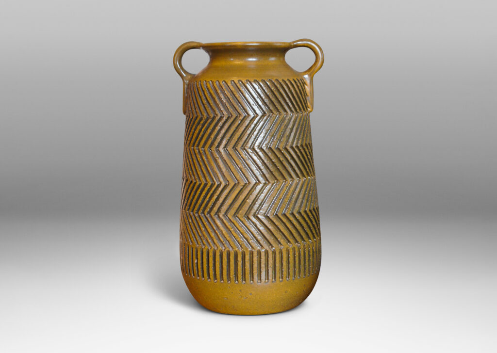 Gallery BAC raked cylindrical forms with cove necks and handles, and featuring the designer’s trademark carved graphic patterning