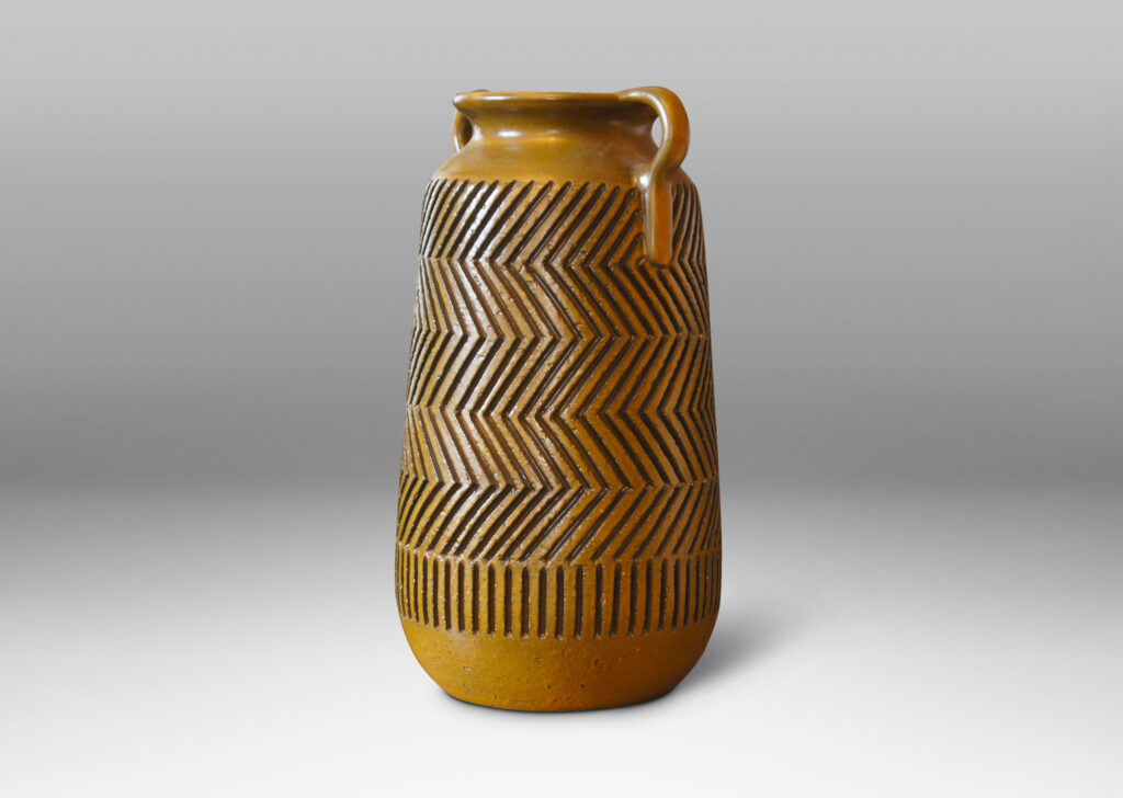 Gallery BAC raked cylindrical forms with cove necks and handles, and featuring the designer’s trademark carved graphic patterning