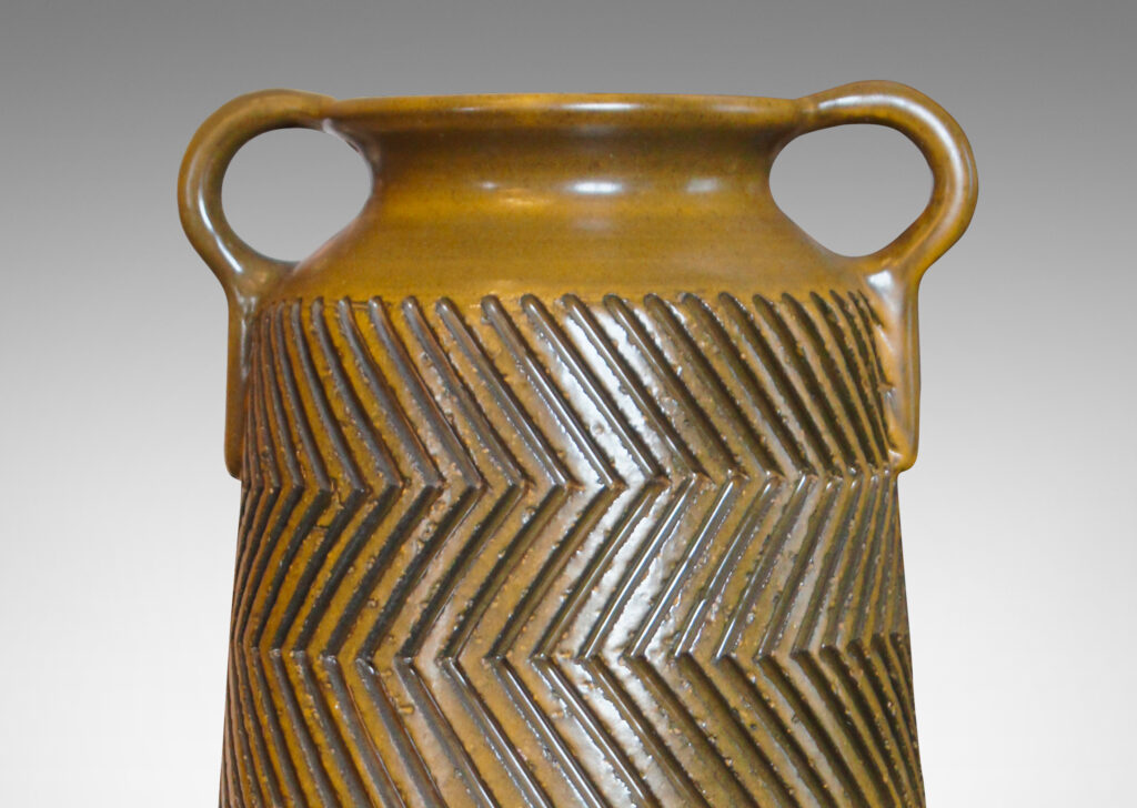 Gallery BAC raked cylindrical forms with cove necks and handles, and featuring the designer’s trademark carved graphic patterning