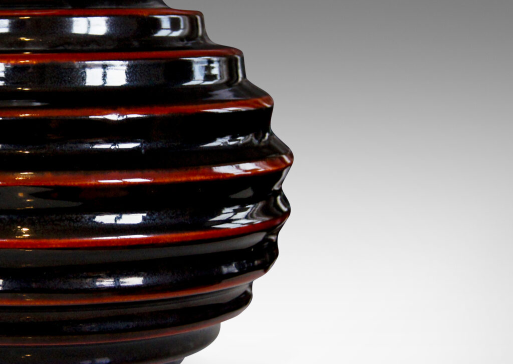 Gallery BAC wide globe form with deep and sculptural horizontal fluting and black glaze with scarlet pinstripes