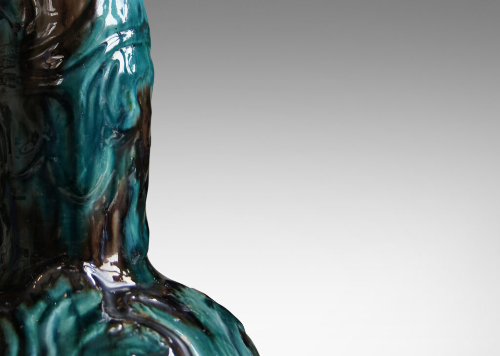 Gallery BAC decanter-like form with low wide body and tall neck, with carved swirling motifs in flowing teal and brown glazing