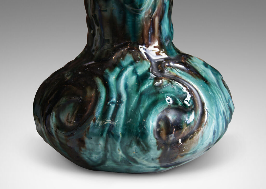 Gallery BAC decanter-like form with low wide body and tall neck, with carved swirling motifs in flowing teal and brown glazing