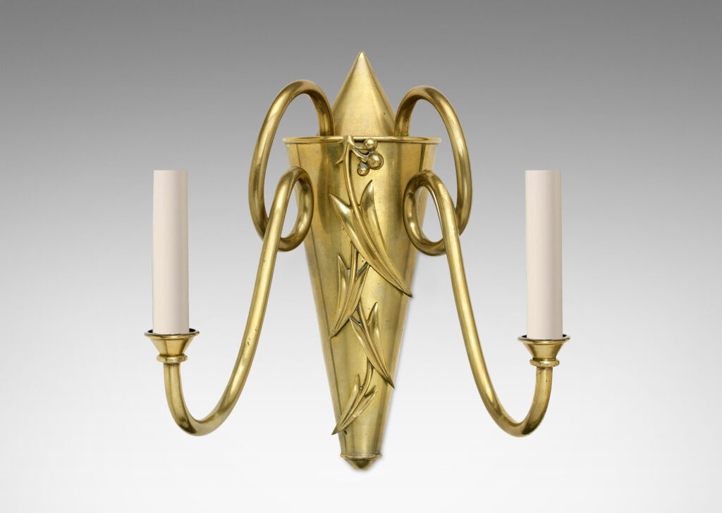 Gallery BAC two candelabra sockets on looping arms springing from a conical backplate ornamented with applied stylized leaves