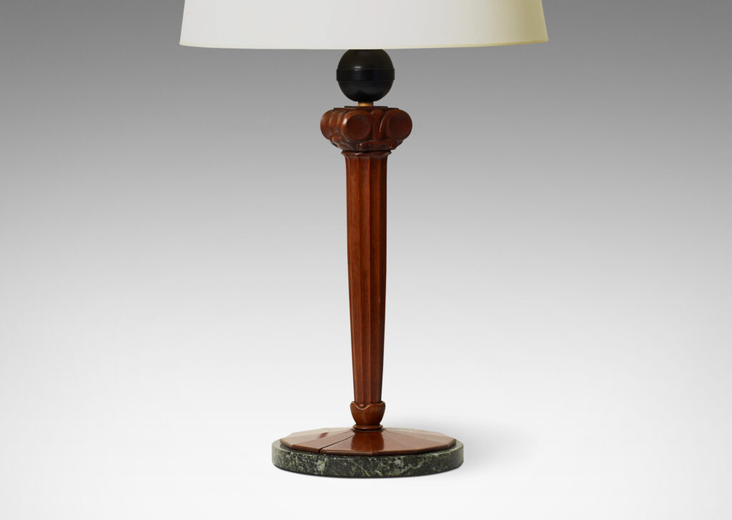 Gallery BAC base comprised of a lobed column capped with volutes, balanced on an ebonized wood sphere perched atop a round base sculpted in radiating planes mounted on a green marble disk