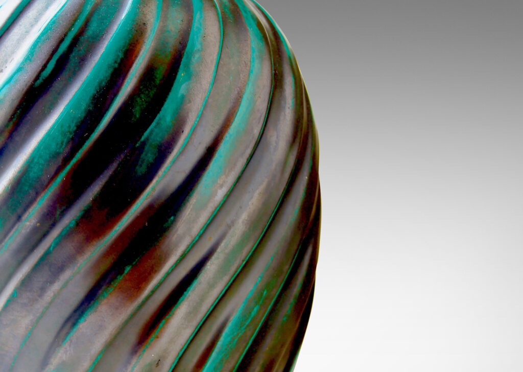 Gallery BAC ovoid form enveloped in a relief pattern of swirling flutes and a sumptuously deep-bluish green copper-oxide glaze