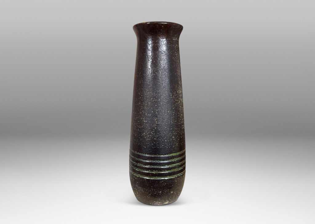 Gallery BAC elongated textured form with flared mouth and carved banding glazed in black over pale green-gray on the outside and burgundy inside