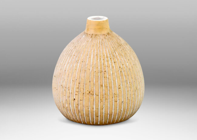 Gallery BAC bulbous form with spout mouth and carved vertical stripes in a speckled tan earthenware partially glazed gloss white in the stripes and inside