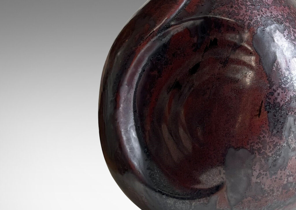 Gallery BAC sculptural bulbous form with round inset design in a burgundy/oxblood-gunmetal luster glaze