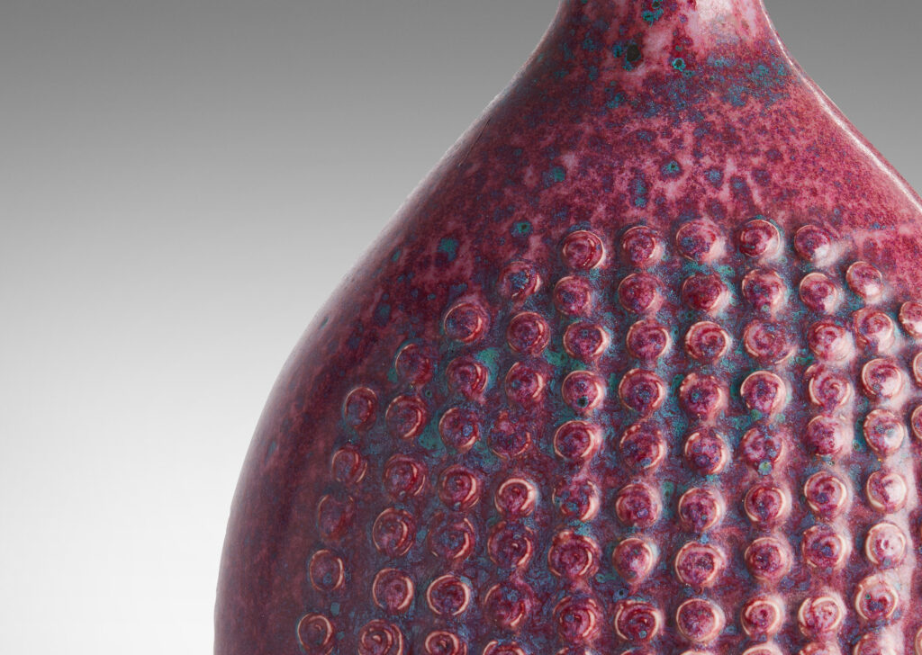 Gallery BAC bottle form with knob texture on front and back and a magnificent mottled raspberry glaze