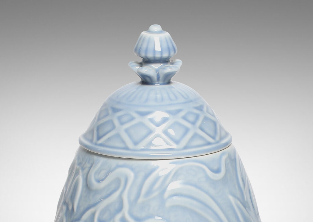 Gallery BAC egg form (a bird reference itself) atop a small angled foot, lid with floral finial atop, vase having continuous relief of birds, leaves and flowers