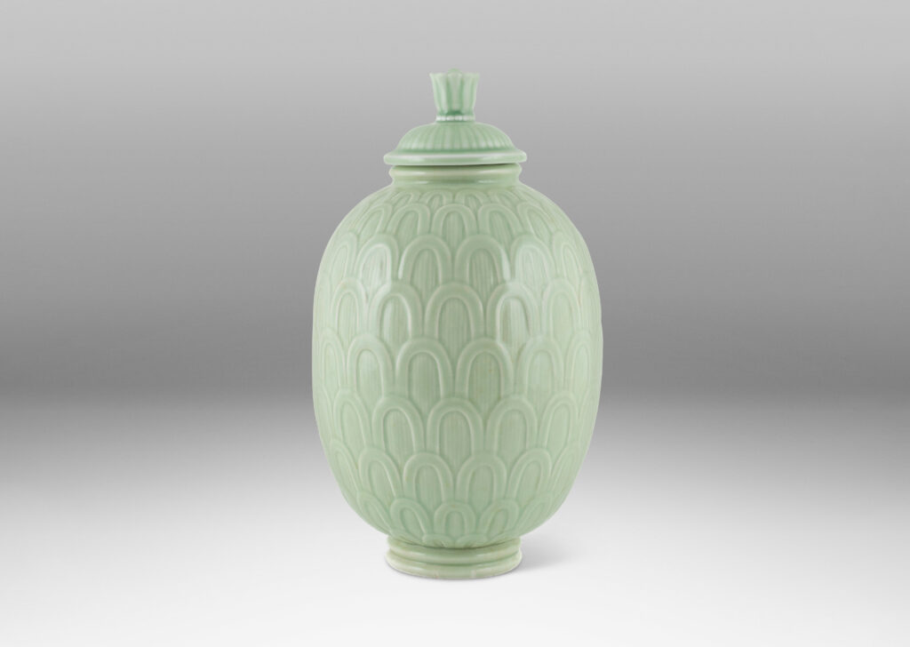 Gallery BAC ovoid form decorated with an overlapping scale pattern in relief and tassel finial on top, glazed in a very handsome pale celadon