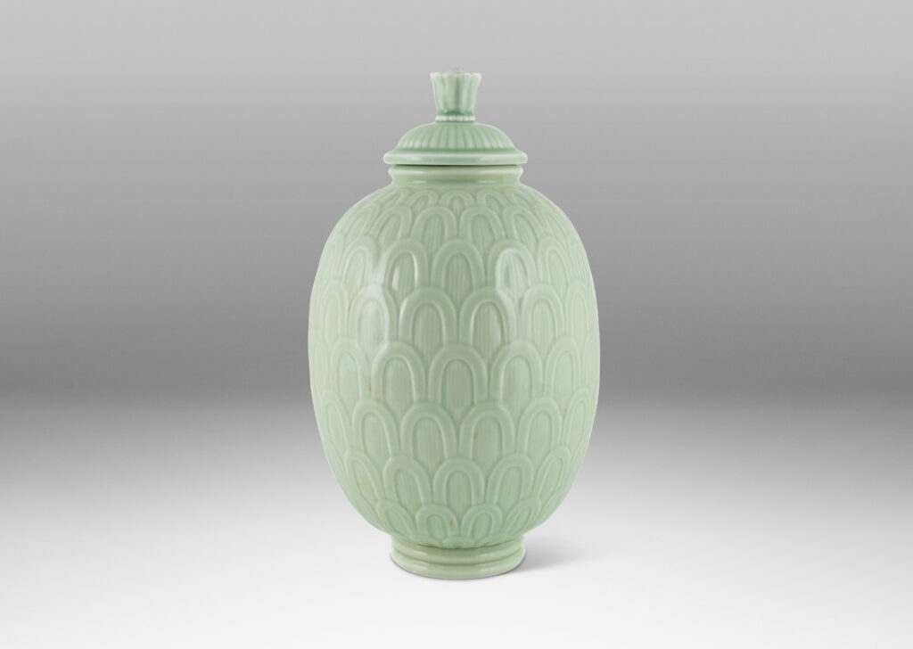 Gallery BAC ovoid form decorated with an overlapping scale pattern in relief and tassel finial on top, glazed in a very handsome pale celadon