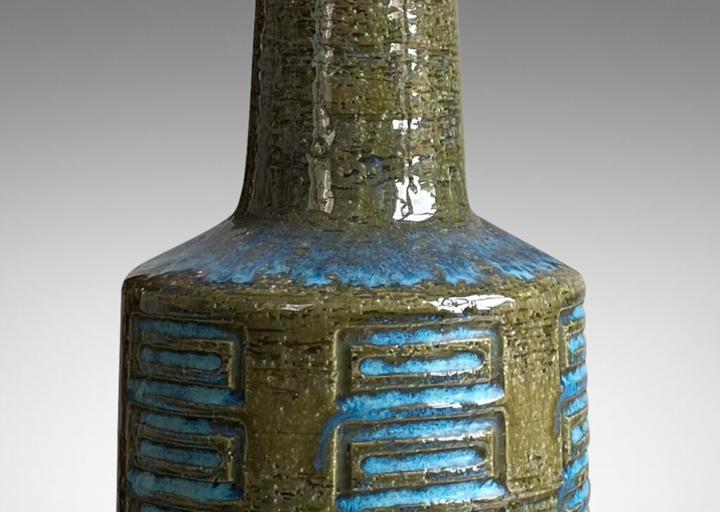 Gallery BAC cylindrical form with tall neck and pattern of carved rectangle motifs; glazed in olive green with turquoise accents