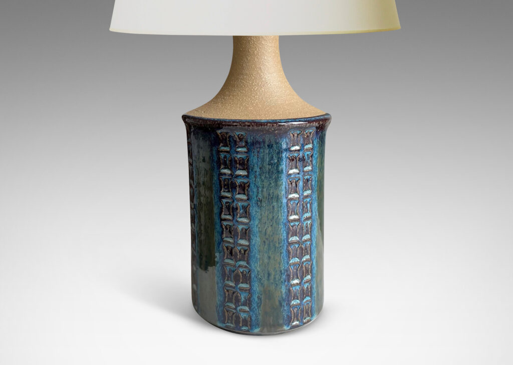 Gallery BAC apering cylinder forms with vertical stripes of impressed motifs glazed in a blue luster, with springing neck in a matte sandy ton