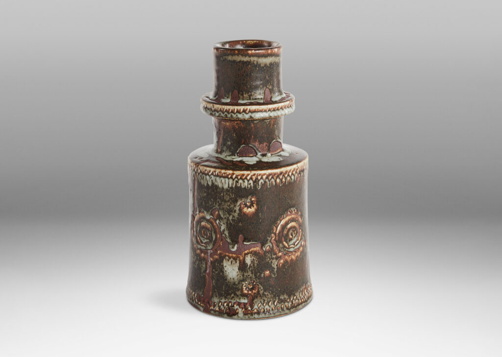 Gallery BAC tiered, stupa-like form, with cylindrical body, wide neck with suspended flange, and impressed ornaments, in brown with touches of pale bluish gray