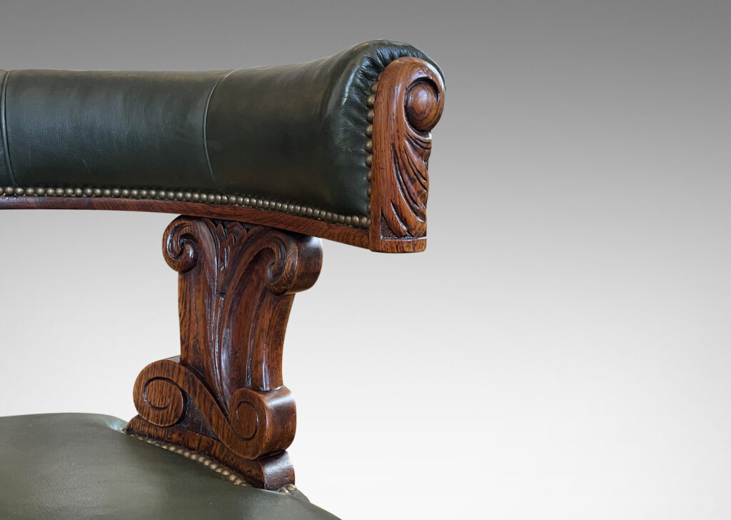 Gallery BAC curved back rail/arms with carved ends on supports with carved acanthus foliate design, in oak with leather upholstery in a subtle green tone