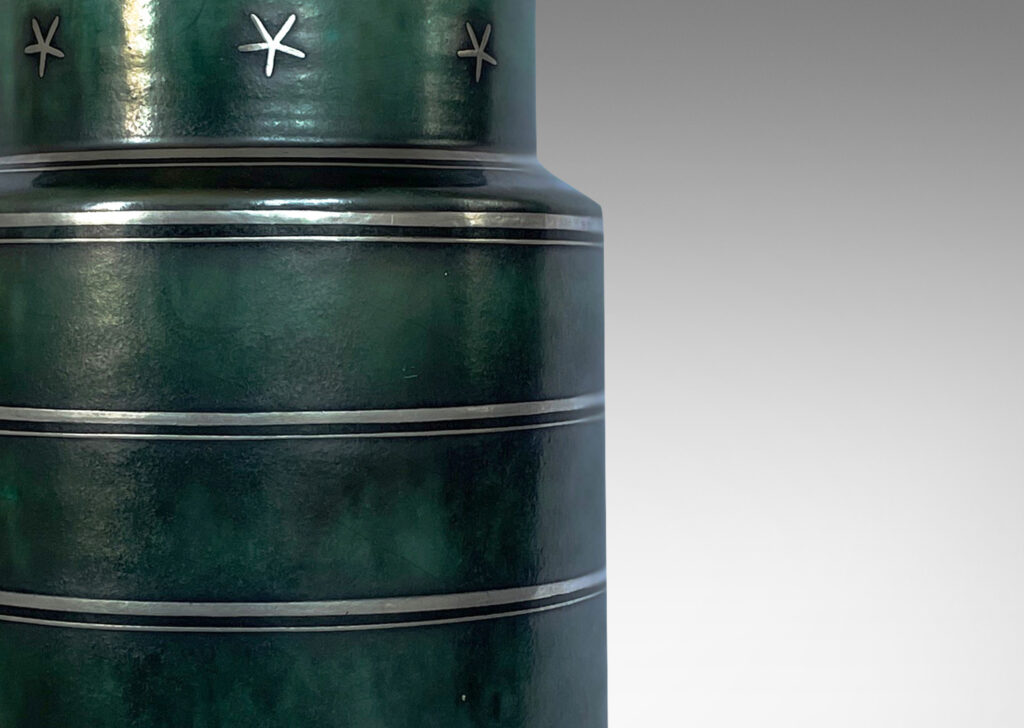 Gallery BAC cylindrical for with inset neck crafted in stoneware with a deep green-blue copper oxide glaze inlaid with stripes and stars in silver