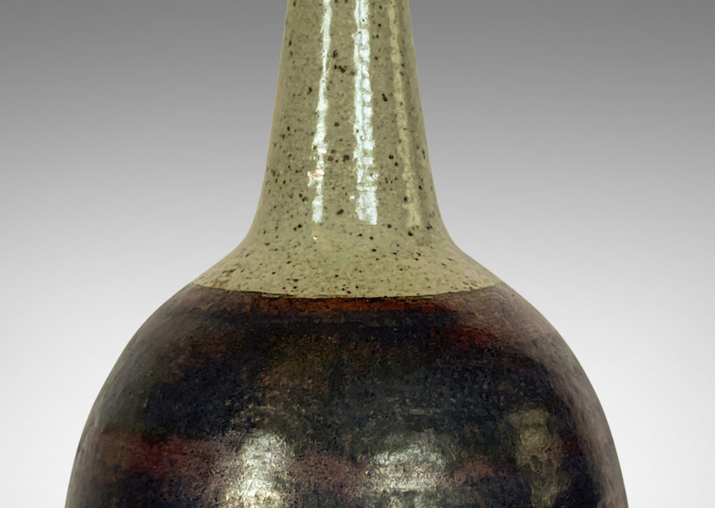 Gallery BAC bulbous form with tall, conical neck, glazed in a black and burgundy luster and speckled gray