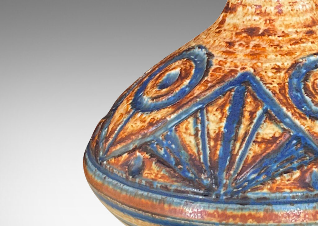 Gallery BAC angled decanter form with carved abstract floral design and stripes in mottled caramel brown with blue-gray glazing