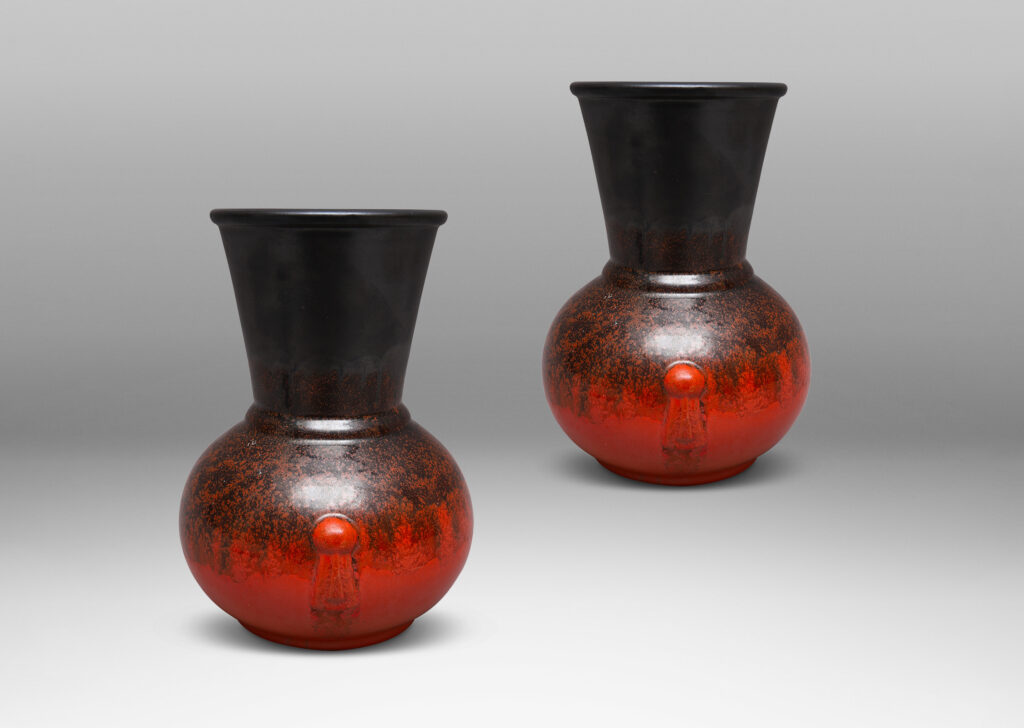 Gallery BAC carafe-like forms with flared necks and relief tassel "handles" in a deep orange and gunmetal gray