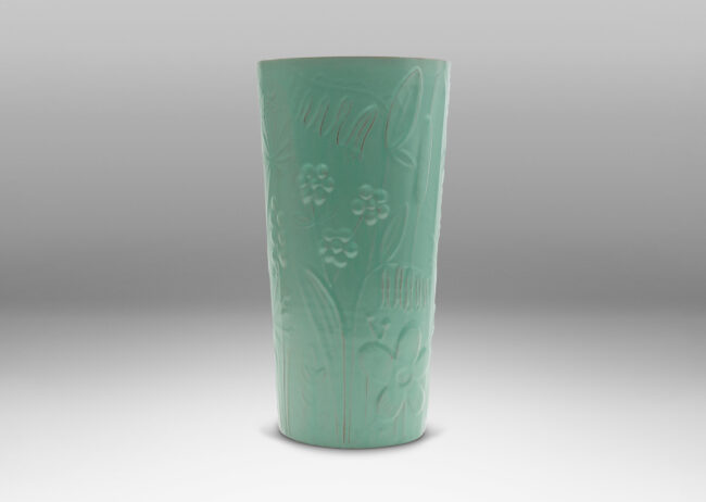 Gallery BAC tall cylindrical form surrounded in floral reliefs and glazed in an eggshell finish celadon