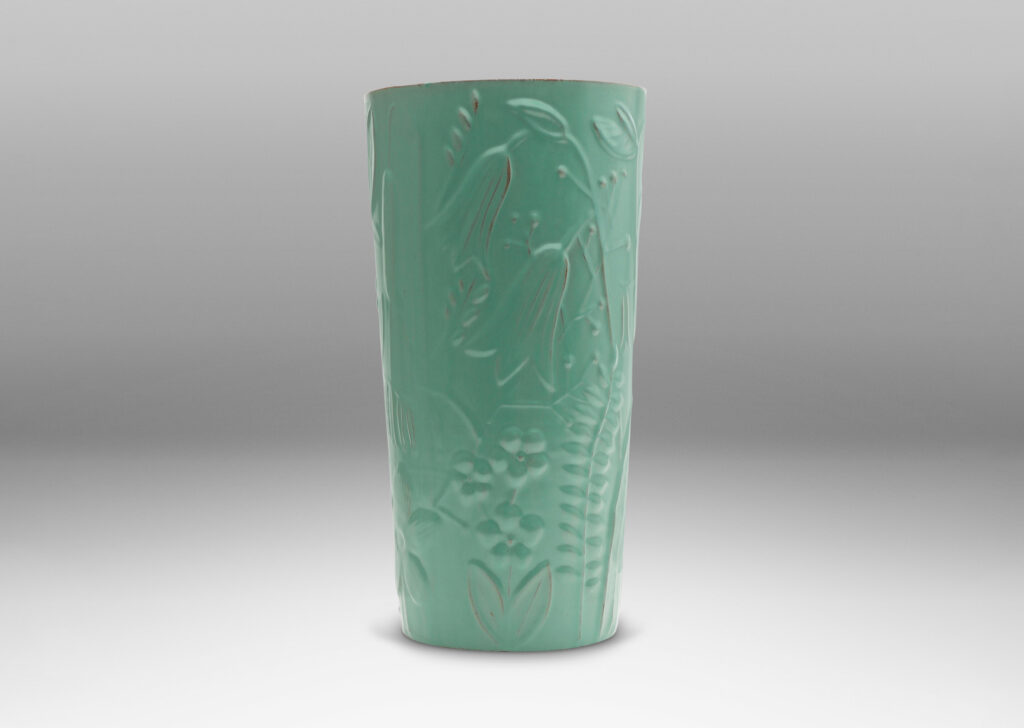 Gallery BAC tall cylindrical form surrounded in floral reliefs and glazed in an eggshell finish celadon