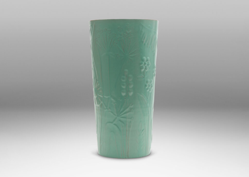 Gallery BAC tall cylindrical form surrounded in floral reliefs and glazed in an eggshell finish celadon