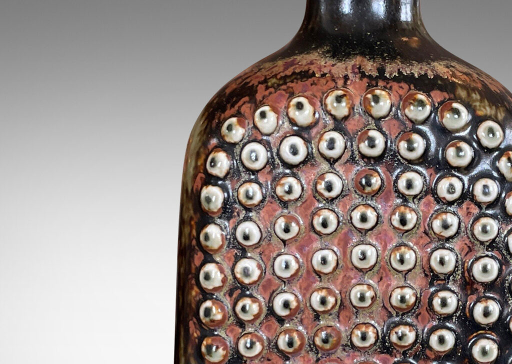 Gallery BAC squared bottle-like form with a grid of cleats on two sides in a dark brown glaze with hints of rust