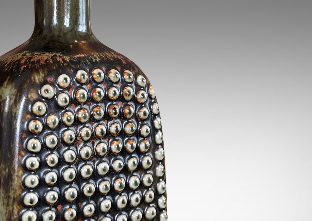 Gallery BAC squared bottle-like form with a grid of cleats on two sides in a dark brown glaze with hints of rust