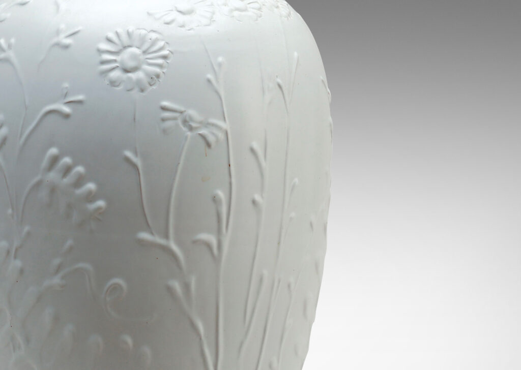 Gallery BAC tall tapering form with relief depictions of wildflowers and an eggshell white finish