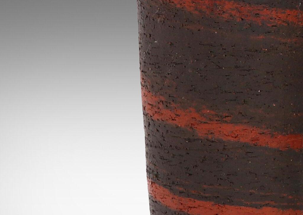 Gallery BAC elegantly modeled tapering forms with a rustic, toothy finish, in matte black with spiraling splashes of rust red