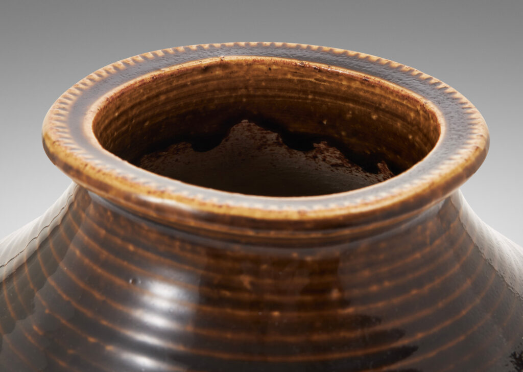 Gallery BAC wide half-spherical form with cove neck and wide mouth with squared lip, with turning grooves and carved chevrons catching a flowing brown glaze