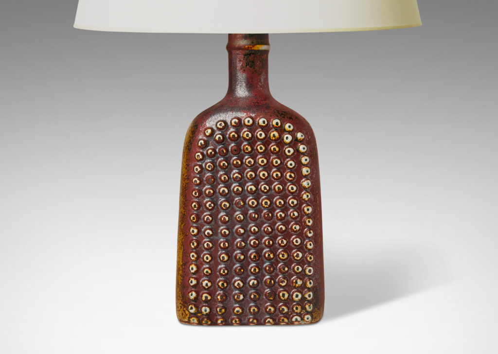 Gallery BAC bottle-like form with grids of cleats in reliefs on two sides and an uncommon dappled oxblood glaze with black accents