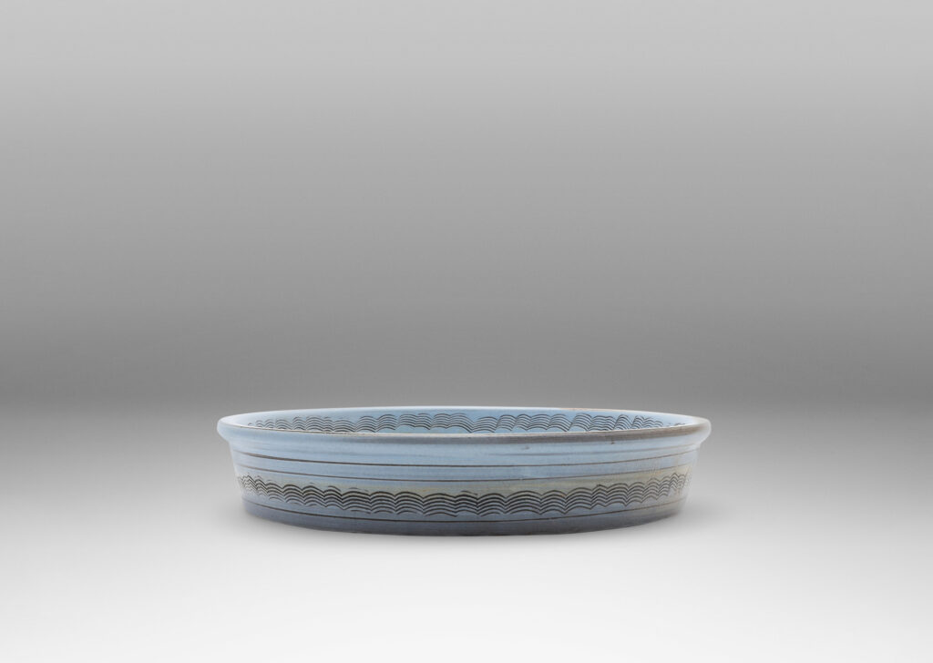 Gallery BAC flat round form with gently angled sides, decorated with concentric combed wave bands, and glazed pale blue