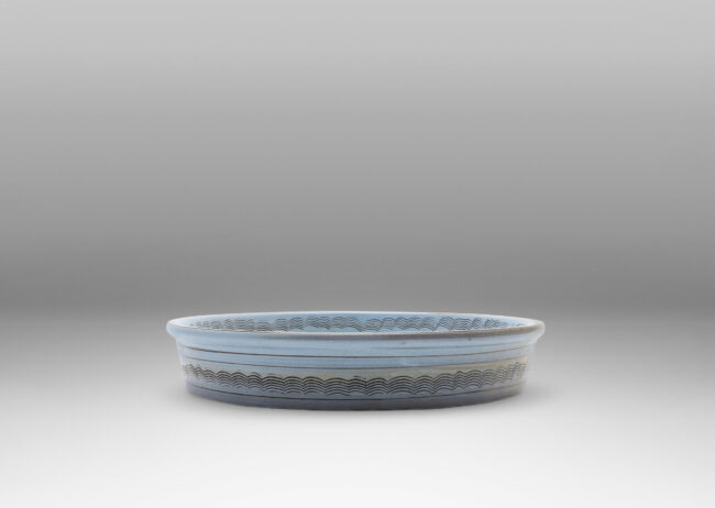 Gallery BAC flat round form with gently angled sides, decorated with concentric combed wave bands, and glazed pale blue