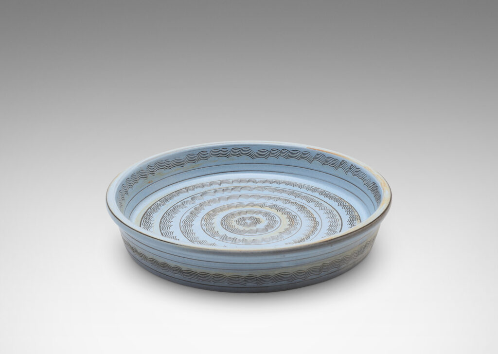 Gallery BAC flat round form with gently angled sides, decorated with concentric combed wave bands, and glazed pale blue