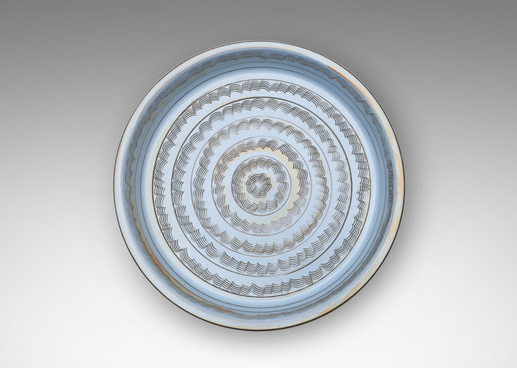 Gallery BAC flat round form with gently angled sides, decorated with concentric combed wave bands, and glazed pale blue