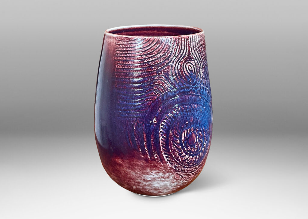 Gallery BAC Gallery BAC ovoid form with wide mouth and carved organic coiling and radiating linear pattern, glazed in oxblood with hints of purple and pale gray