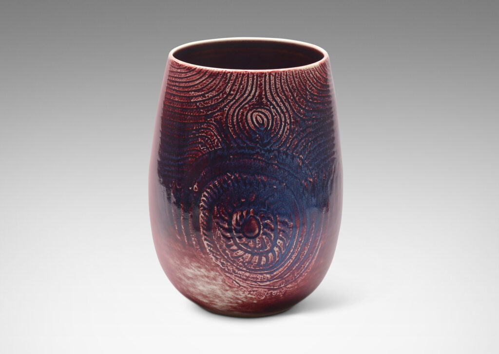 Gallery BAC Gallery BAC ovoid form with wide mouth and carved organic coiling and radiating linear pattern, glazed in oxblood with hints of purple and pale gray